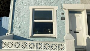 A two-story house with a white door, a small balcony with a white railing, and a number '20' on the wall. - Min y Graig, New Quay (New Quay)