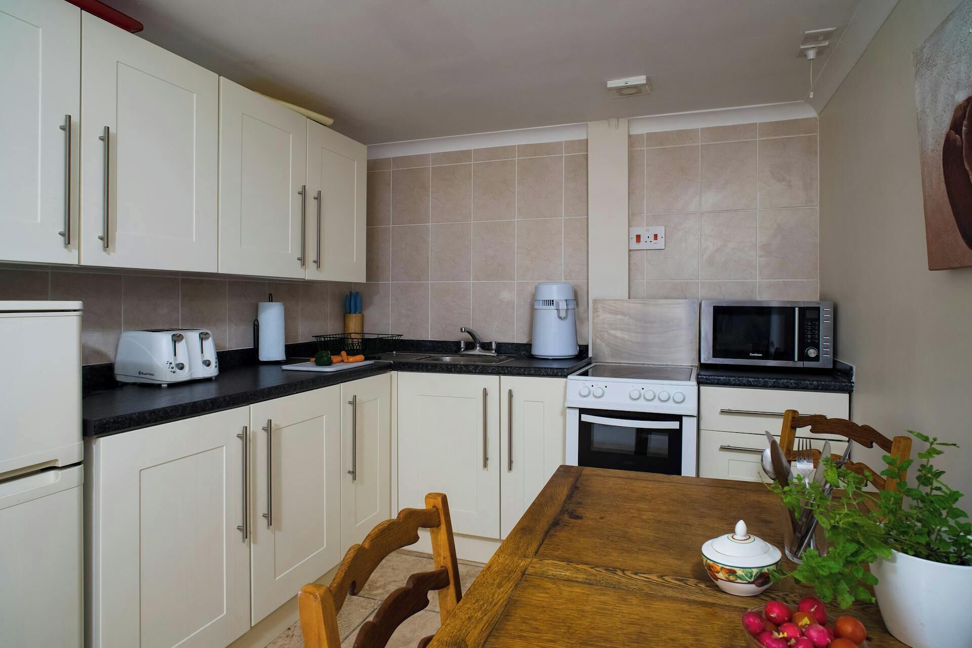 A kitchen with white cabinets, a microwave, a toaster, and a stove.