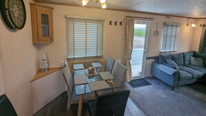 A cozy living room with a dining table, a sofa, and a cabinet. - Beach House Dog Friendly - Anderby Creek (Skegness)