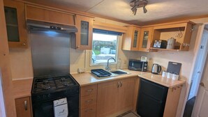 A compact kitchen with a gas stove, oven, microwave, sink, and a small refrigerator. - Beach House Dog Friendly - Anderby Creek (Skegness)