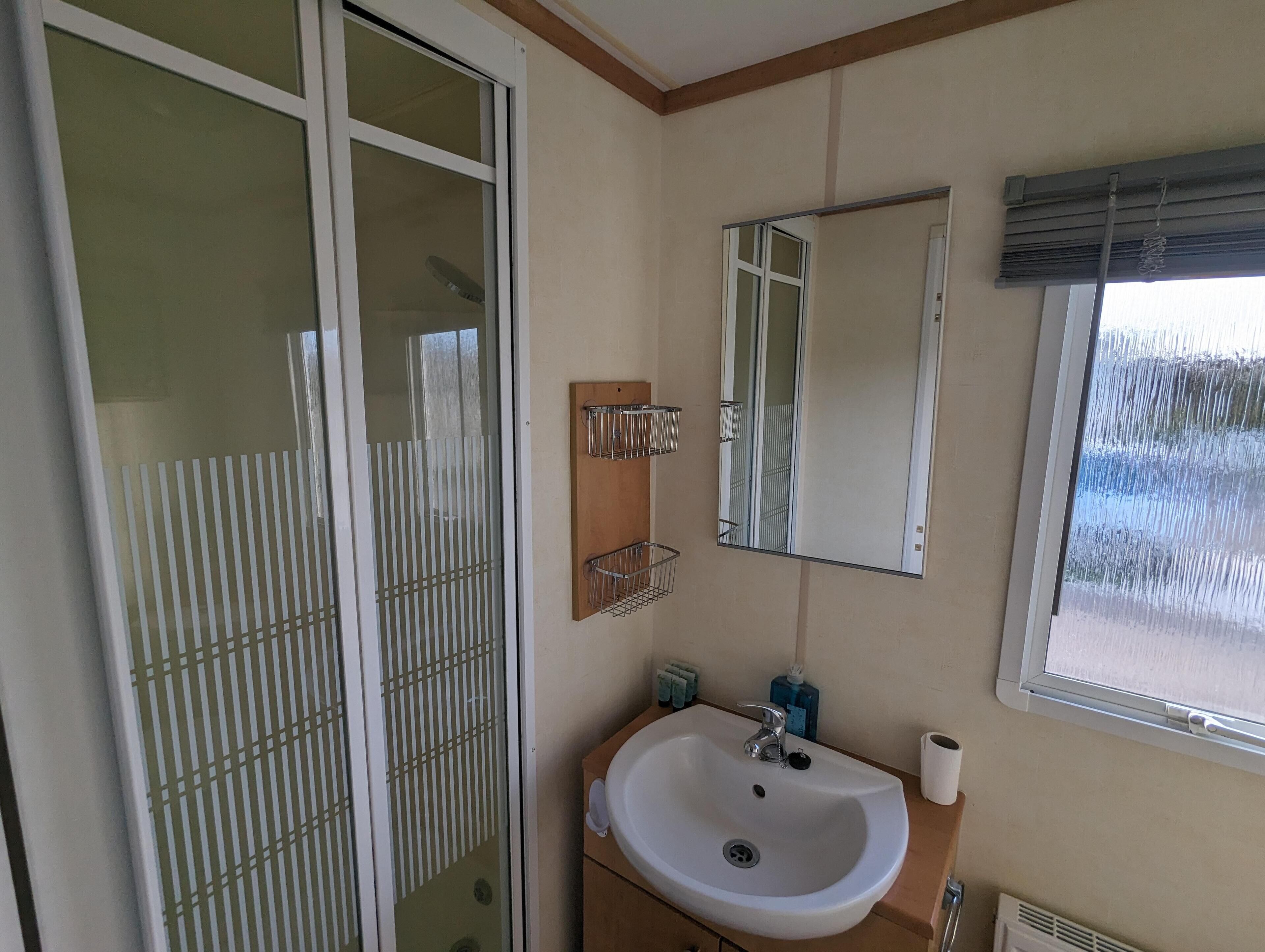 A bathroom with a white sink, mirror, and window.