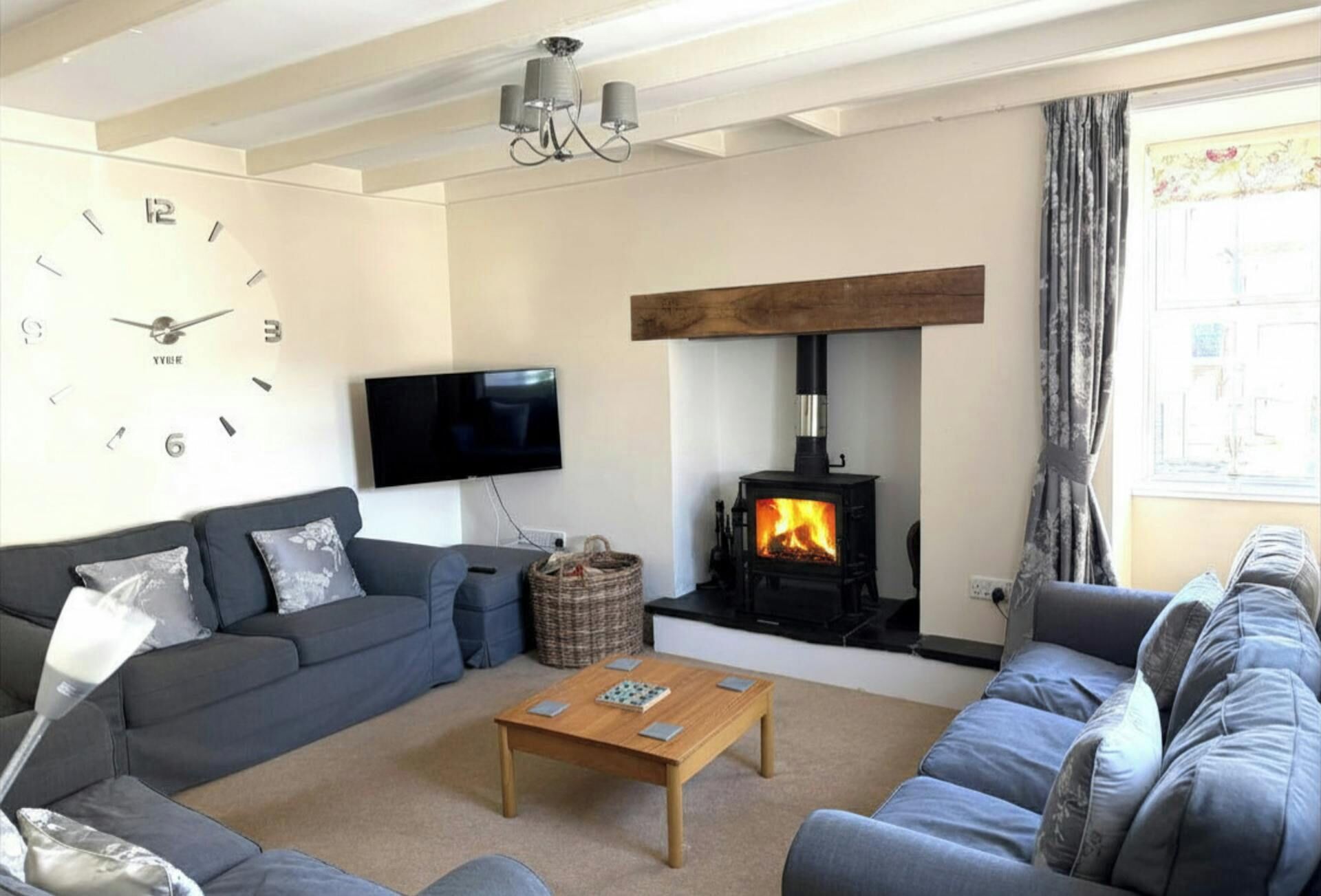 A living room with a sofa, a coffee table, a fireplace, a television, and a clock.