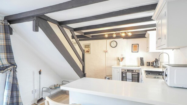 A kitchen with a white countertop, a clock, and a window. - The Coach House, Newcastle Emlyn (Newcastle Emlyn)