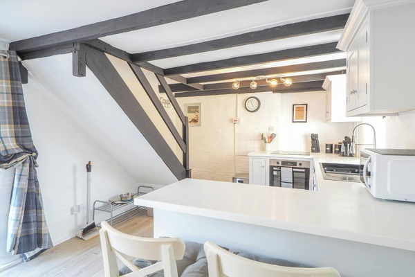 Bright kitchen with breakfast bar, stairs leading to first floor, fitted units