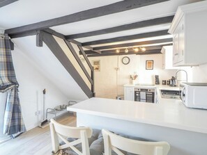 A kitchen with a white countertop, a clock, and a window.