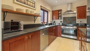 Une cuisine moderne avec des meubles en bois, un four encastré, une cuisinière et un lave-vaisselle.