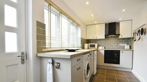 A compact kitchen with a washing machine, microwave, and oven.