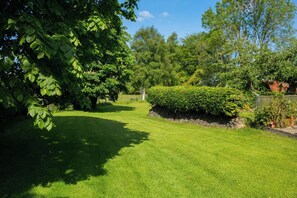 A well-maintained garden with a variety of trees and a neatly trimmed hedge.