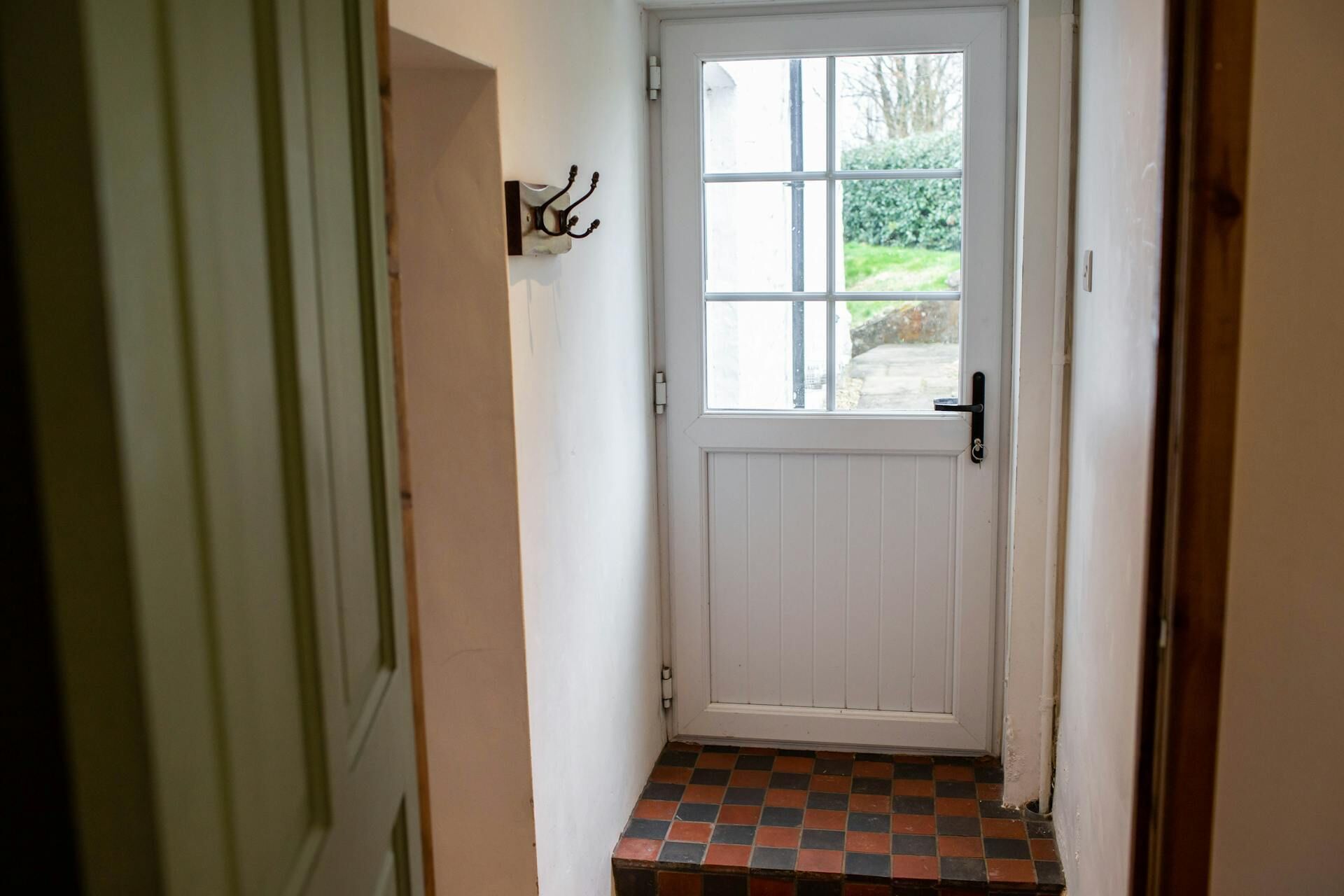 A white door with a small step leading to a tiled entrance.