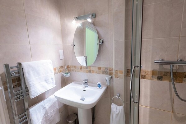 Un bagno con lavandino bianco, specchio, porta asciugamani e doccia.