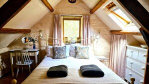 A cozy attic bedroom with a bed, a small desk, and a window with curtains. - Y Beudy, Llangrannog (Llangrannog)