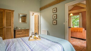 Ein Schlafzimmer mit Bett, Kommode und Blick ins Freie.