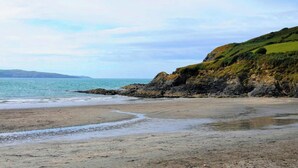 Une plage côtière bordée de falaises rocheuses, sous un ciel dégagé.