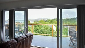 Un balcon donnant sur un paysage verdoyant et un plan d’eau.
