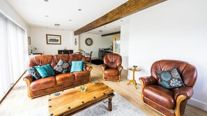 Un salon avec un canapé en cuir marron, une table basse en bois et un fauteuil en cuir.