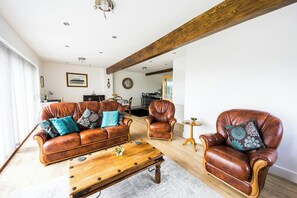 Un salon avec un canapé en cuir marron, une table basse en bois et un fauteuil en cuir.