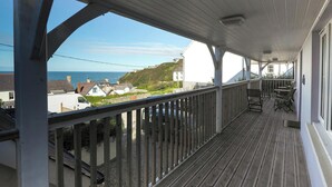 En inglasad balkong med utsikt över havet och husen.