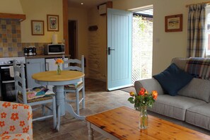 A cozy living area with a dining table, chairs, a sofa, and a kitchen in the background. - The Hideaway, Aberporth (Brongest)