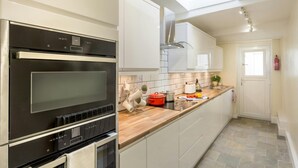 Eine moderne Küche mit eingebautem Backofen, einem Oberlicht und einer Holz Arbeitsplatte.