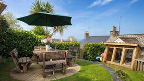 A wooden outdoor table with chairs, a green umbrella, and a potted plant. - Y Bwthyn, Newport - Two Bedroom Cottage, Sleeps 4 (Newport)