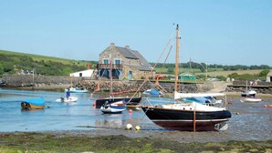 A coastal village with boats docked at a harbor, a stone building, and a grassy hillside in the background. - Y Bwthyn, Newport - Two Bedroom Cottage, Sleeps 4 (Newport)