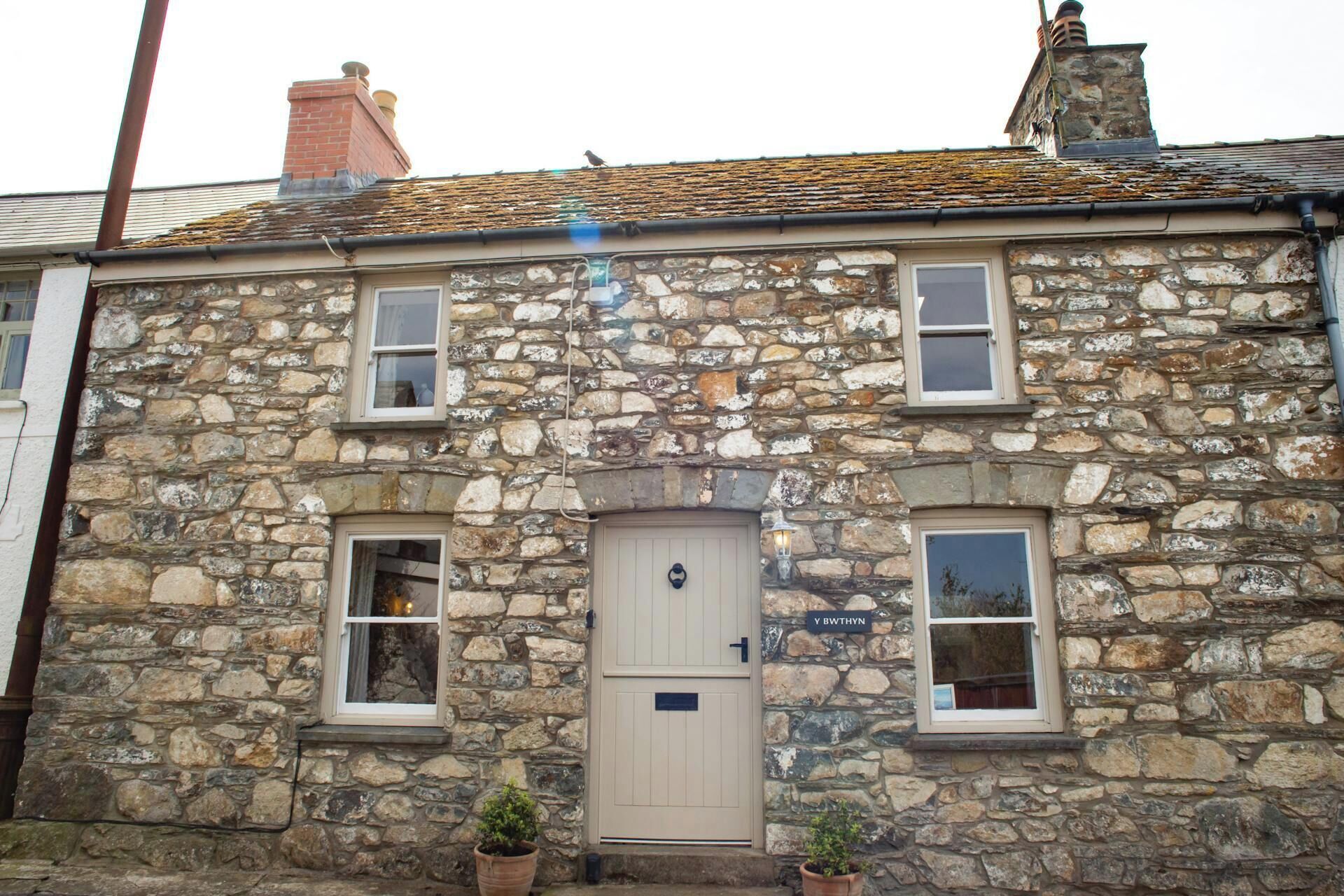 A stone building with a central door, two windows on each side, and a small sign above the door.