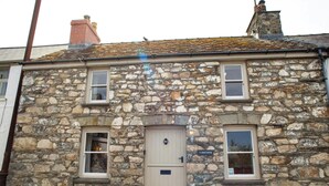 A stone building with a central door, two windows on each side, and a small sign above the door. - Y Bwthyn, Newport - Two Bedroom Cottage, Sleeps 4 (Newport)