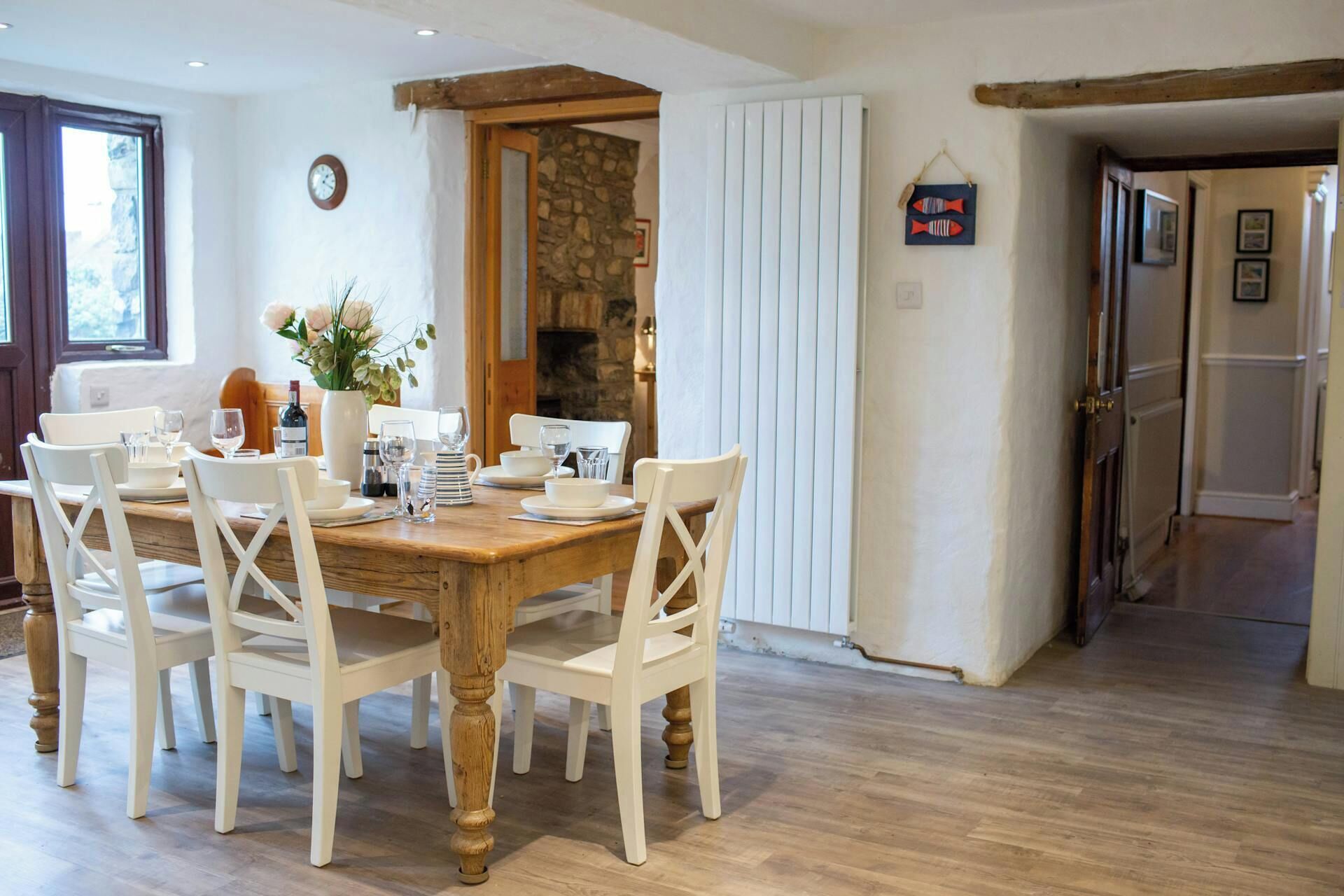 A dining area with a wooden table and white chairs, a stone wall, and a white radiator.