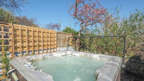 Ein Whirlpool in einer Gartenanlage mit Holzlattenzaun und umliegender Bepflanzung.