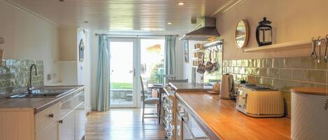 A kitchen with a wooden countertop, a sink, and a view to the outside.