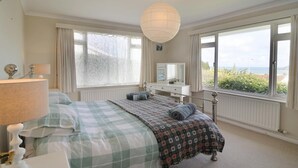 Un dormitorio con cama, cómoda, espejo y vistas al exterior.