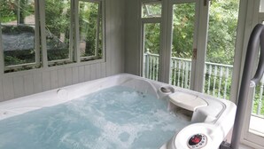 Un bain à remous doté d’un panneau de commande, entouré de grandes fenêtres et agrémenté d’un balcon avec une balustrade.