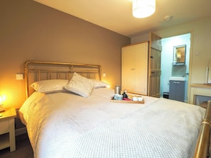 A neatly made bed with pillows, a bedside table with a lamp, and a tray with breakfast items.