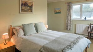 Une chambre à coucher avec un lit, une table de chevet, une lampe et deux tableaux au mur.