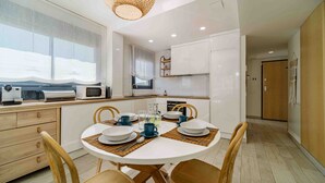 Una cocina moderna con armarios blancos, una mesa de comedor con vajilla azul y blanca, y una lámpara de techo de madera.