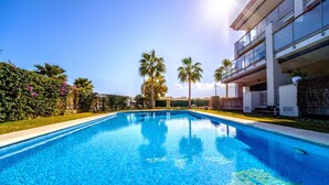 Una piscina azul cristalina con un edificio moderno al fondo.