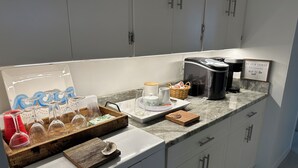 A modern kitchen with white cabinets, a marble countertop, and various kitchen appliances.