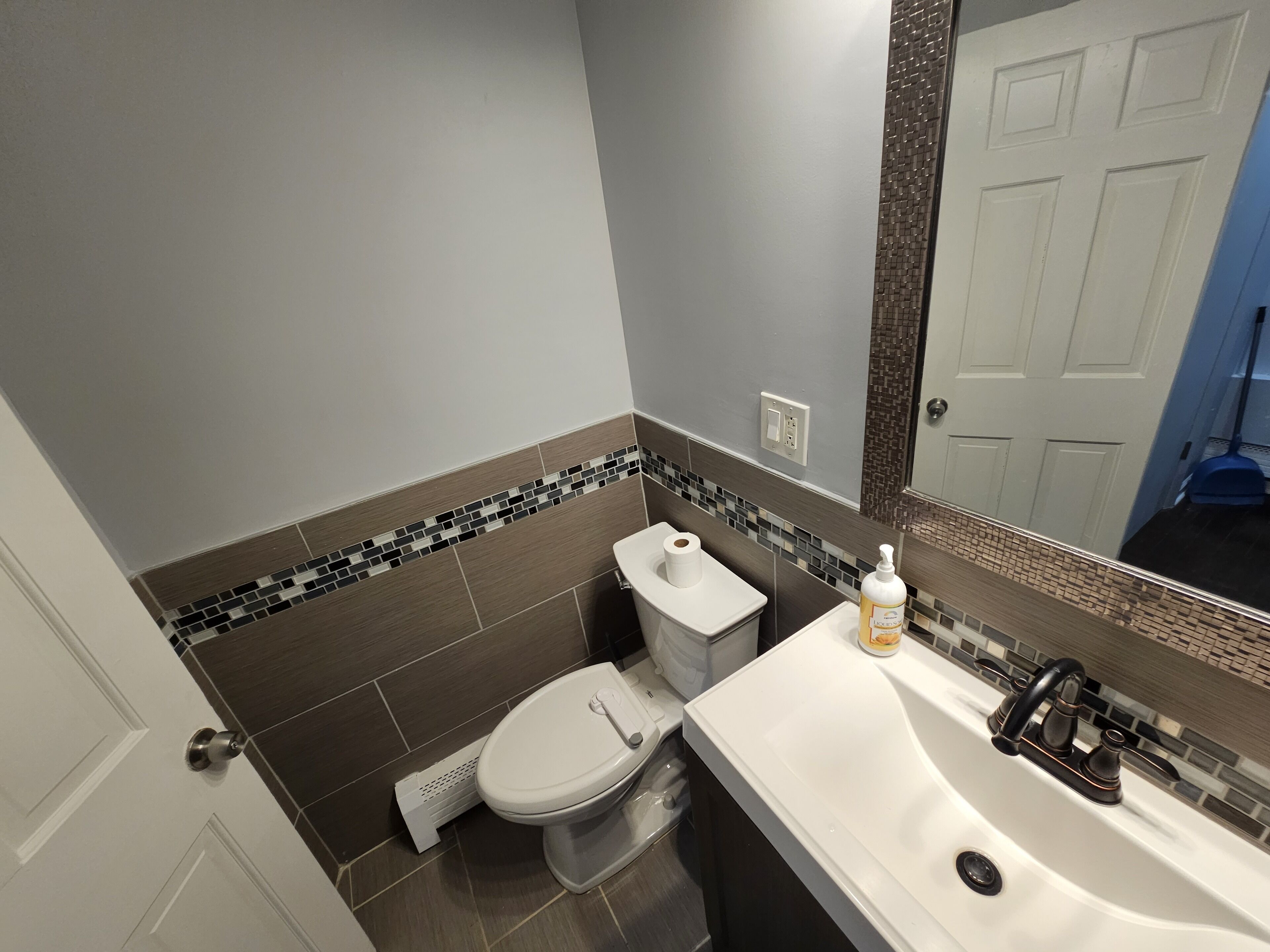 A bathroom with a toilet, sink, and mirror.