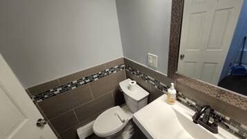 A bathroom with a toilet, sink, and mirror.