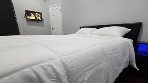 A neatly made bed with white bedding in a room with a dark headboard. - Grandiosely Pleasant Suite 2 (Hempstead)