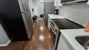 A modern kitchen with stainless steel appliances, a white countertop, and a marble backsplash. - Grandiosely Pleasant Suite 2 (Hempstead)