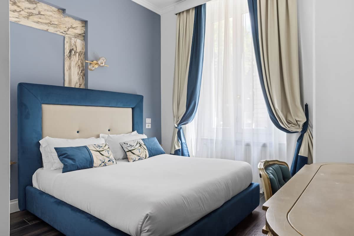 A modern bedroom with a large bed, a headboard, and a dining table.