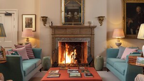 Una sala de estar con chimenea, dos sofás, una mesa de centro con libros y lámparas decorativas.