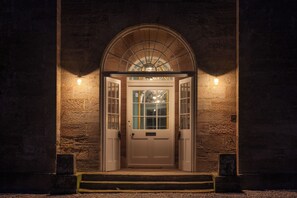 A building entrance with a large arched doorway, a white door, and two wall-mounted lights. - Dabton House (Thornhill)