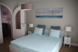 A bedroom with a bed, bedside tables, a lamp, and a painting on the wall. - Magnifique Appartement Côte Belge 100 m. Plage (Westende)