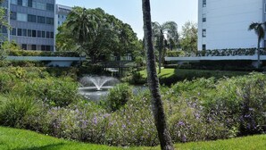 Un giardino curato con fontana, palme e un ponte.