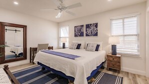 A bedroom with a bed, a ceiling fan, a nightstand, a lamp, and a window with blinds.
