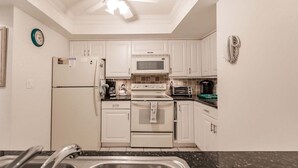Una cocina con armarios blancos, un refrigerador, un microondas, un horno, un tostador y un lavamanos.