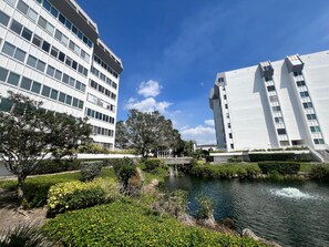 A modern building complex with a river and greenery in the foreground. - 1046 - Premium 1st Floor - Gulf Side Bliss (Siesta Key)