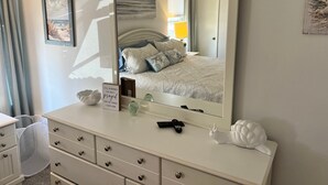 A bedroom with a bed, dresser, mirror, and a sign on the dresser.